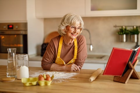 Cookbook author reading her published recipe book beside baking ingredients