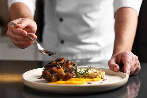 Professional chef finishing a signature dish, the kind of recipe work we turn into cookbooks