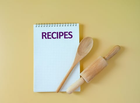 Recipe notes being written in a notebook during cookbook development